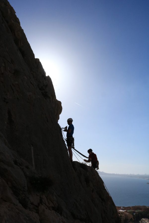 Silhouette of two rock climbers against a blue sky