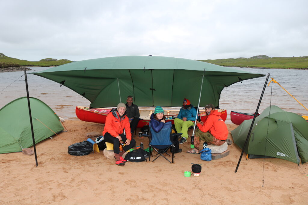 A group under a canopy resting after a day of kayaking on an Active Outdoor Pursuits journey