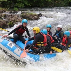 A group of people wearing safety gear, enjoying an Active Outdoor Pursuits white water rafting adventure