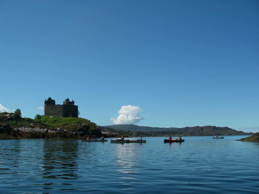 A group on a DofE expedition in canoes on water in front of a castle
