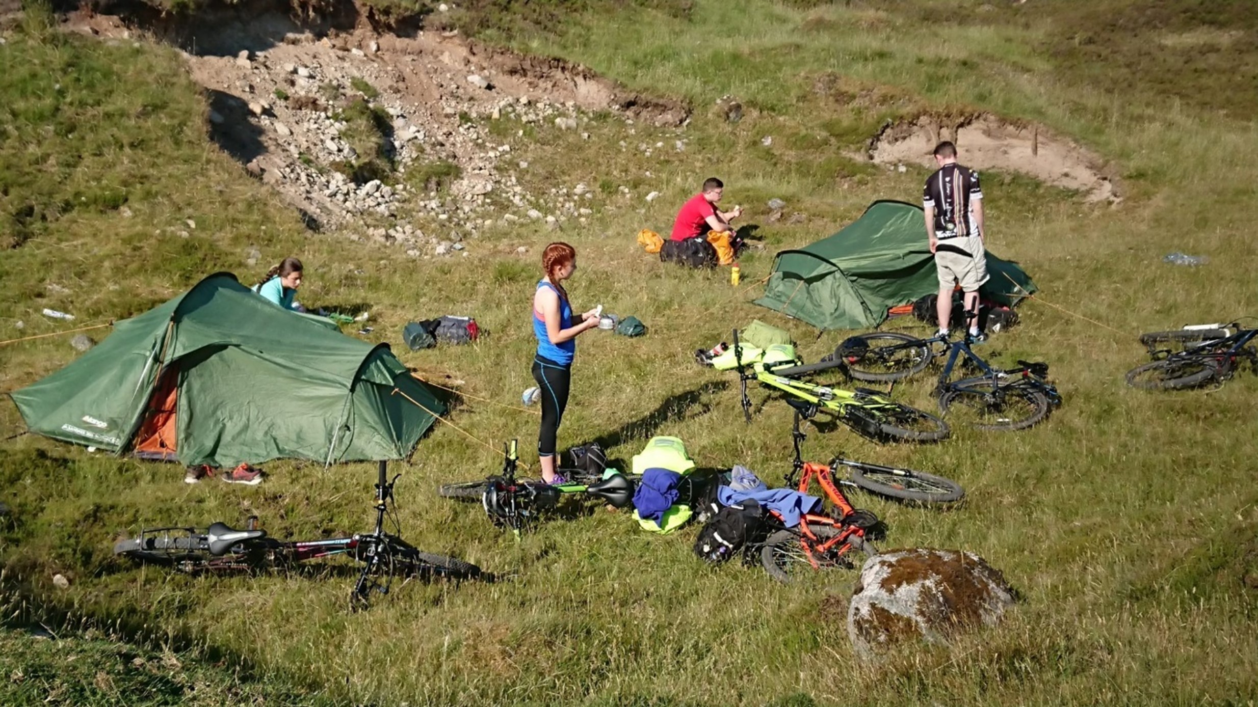 An image of participants setting up tents with bikes on the ground on their Gold DofE mountain biking expeditions, training, practice, and qualifier