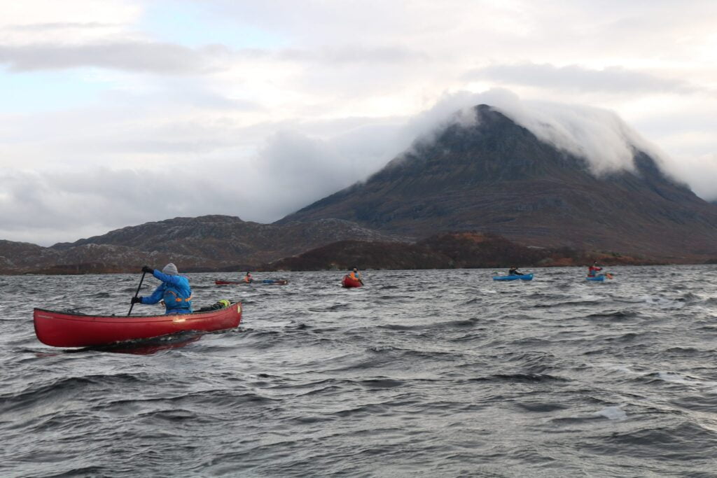 A group of people canoeing with mountains in the background as part of their Gold DofE award.